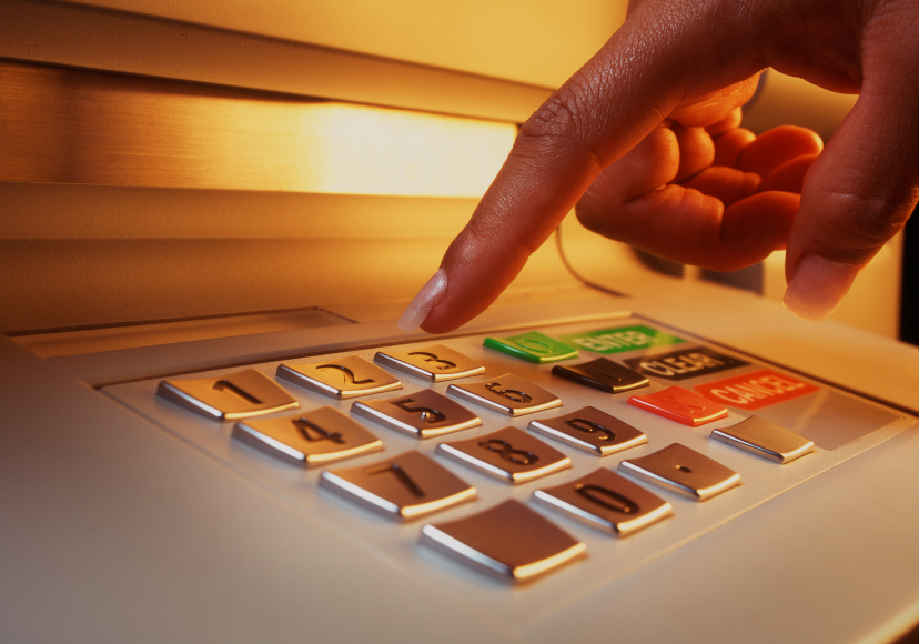 Close-up of a hand pushing buttons on a keypad of an ATM