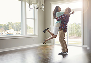 Man holding woman in the air in an empty house on a sunny day