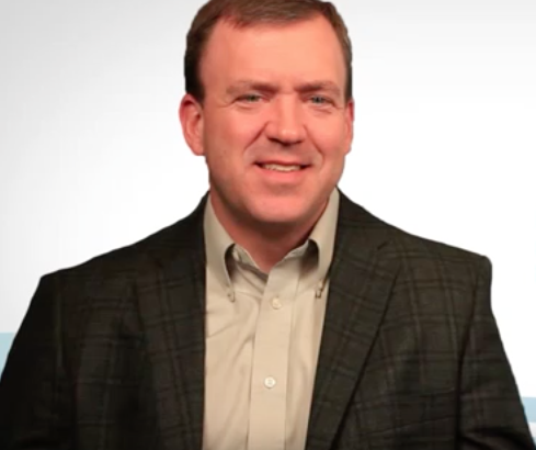 Man with short hair, black plaid jacket, and khaki shirt