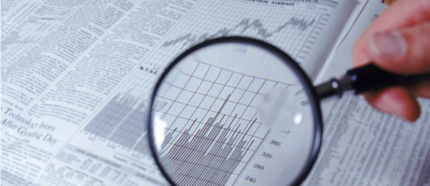 Magnifying glass over a bar graph in the financial news section of a newspaper