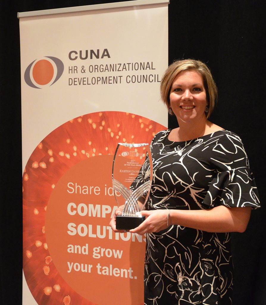 Woman in a black and white dress holding an award for the CUNA HR and Organizational Development Council