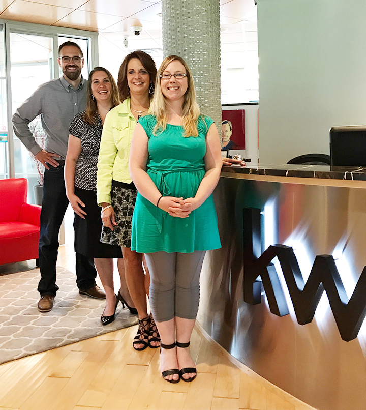 Three women and a man standing in a receptoin area of an office