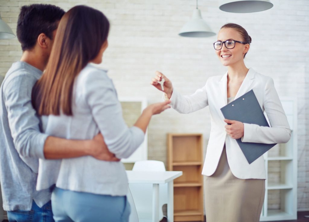 A married couple receiving a set of keys from a real estate agent