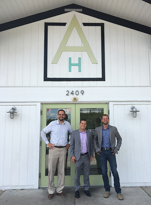 Three men standing outside of a business storefront