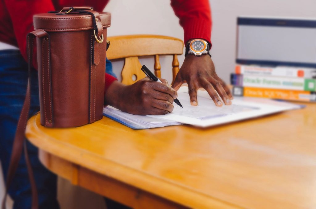 A man standing a dinner table with dry erase tablet writing something down