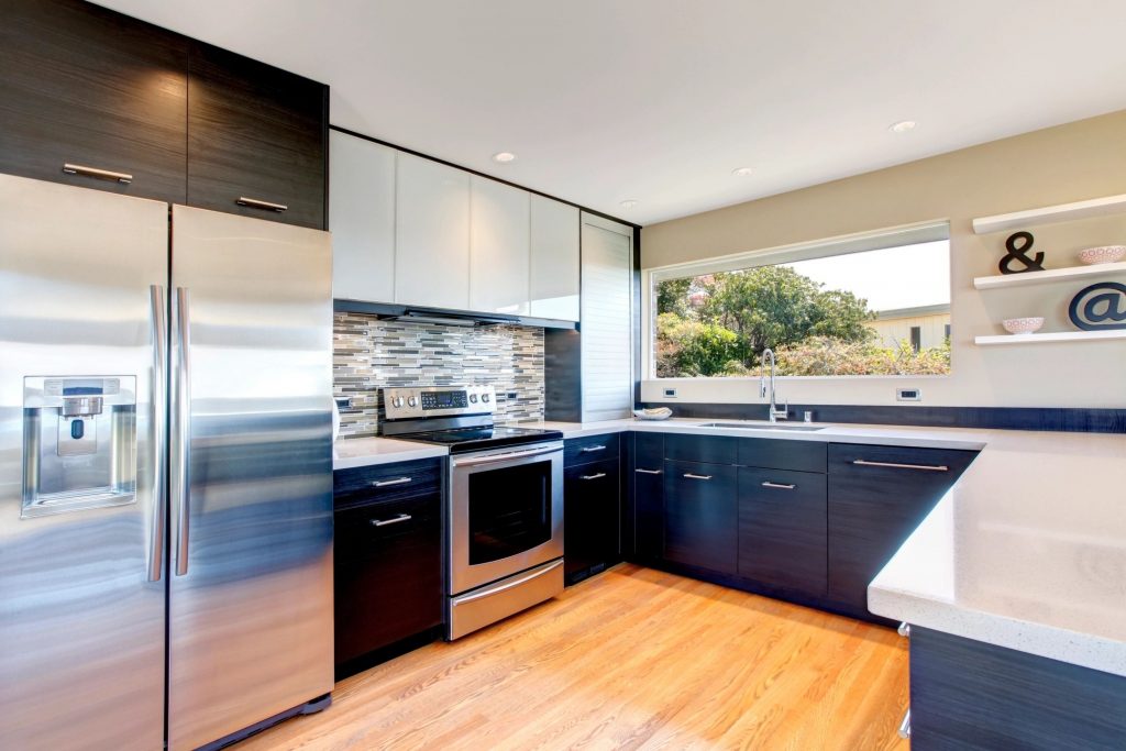 A newly renovated kitchen with hardwood floors and white countertops