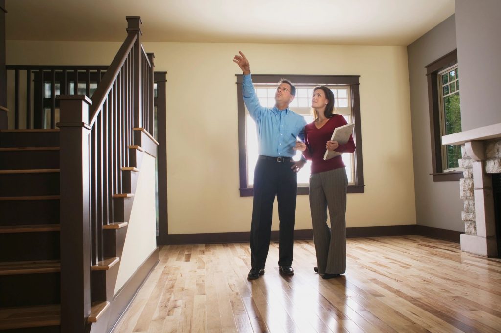 A man and woman standing in an empty living room discussing the house