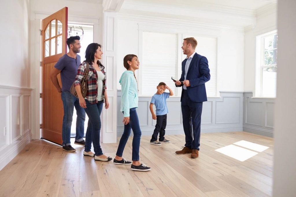 A family walking into an empty home with a real estate agent