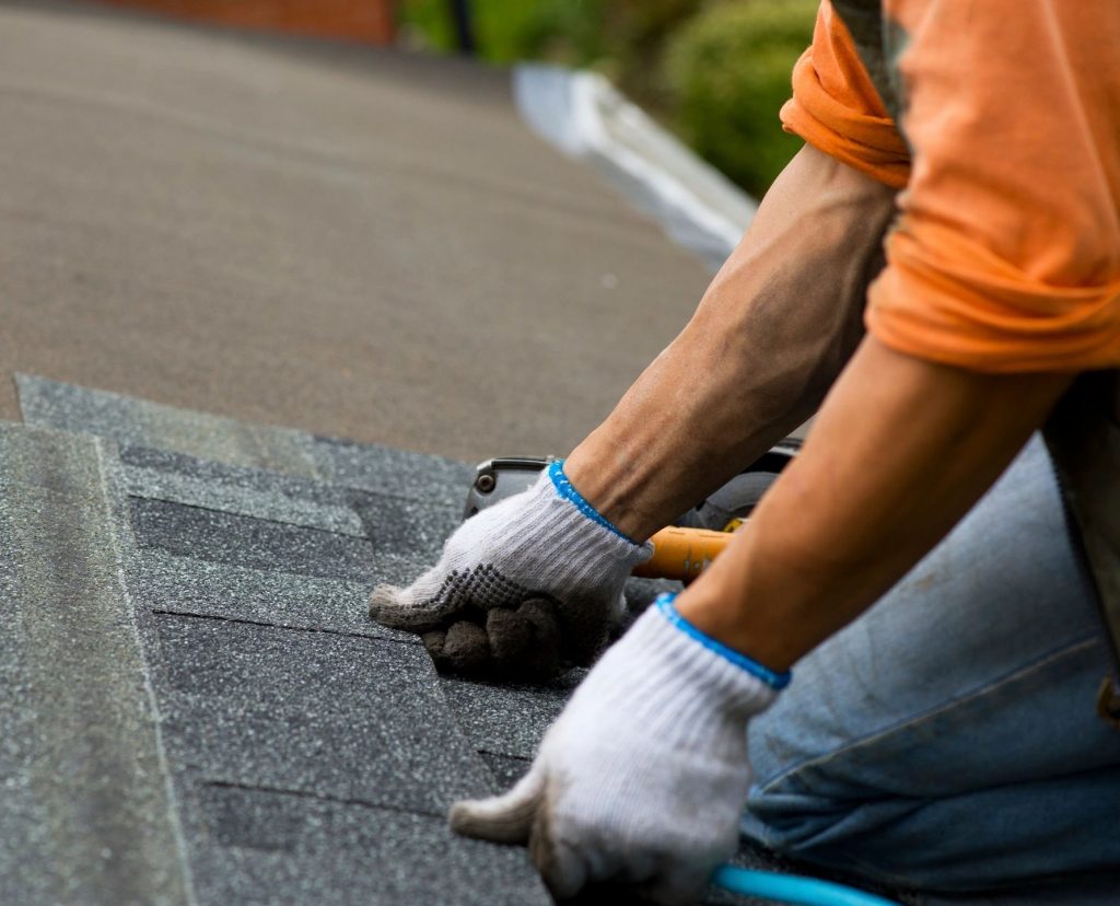 Close up of arms putting shingles on a roof