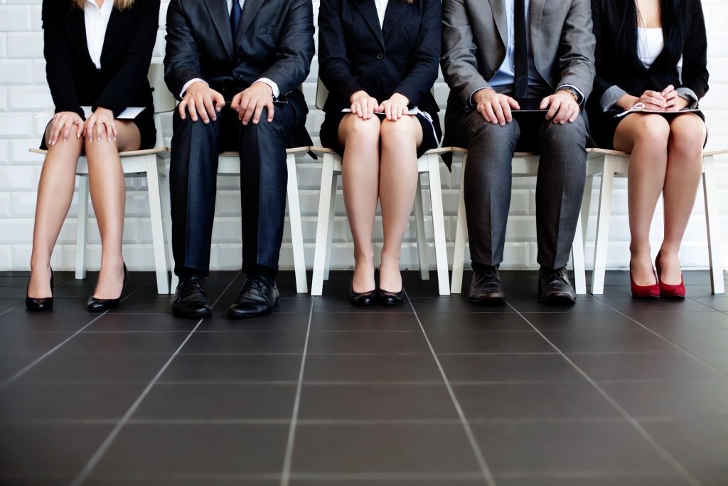 Three women and two men from the shoulders down sitting in chairs