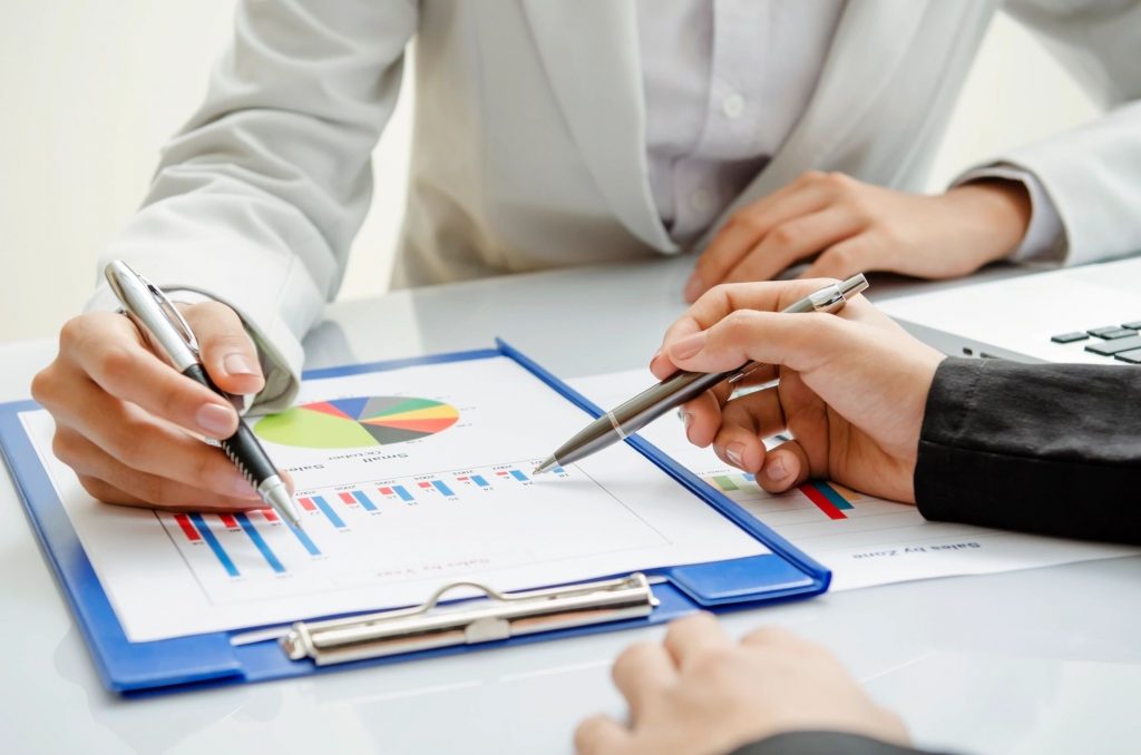 Close-up of two business people discussing graphs