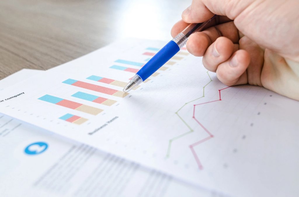 Close-up of a hand with a pen pointing at a bar graph