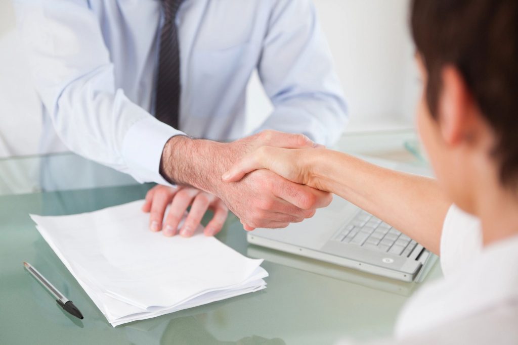 Close-up of two people shaking hands over a table