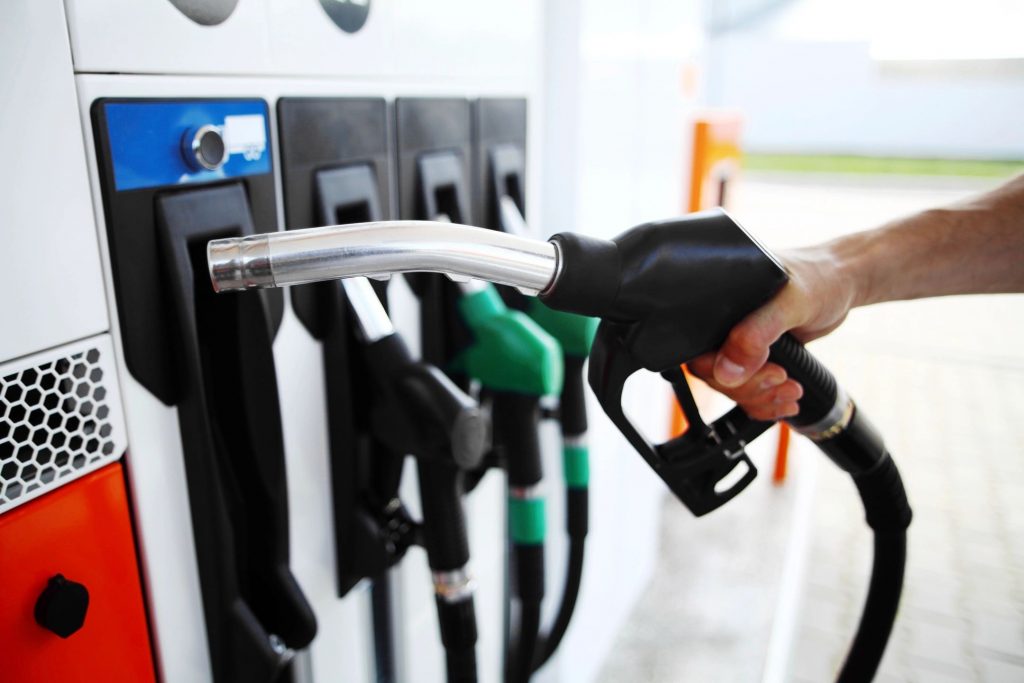 A close-up of a hand holding a fuel nozzle at a gas pump