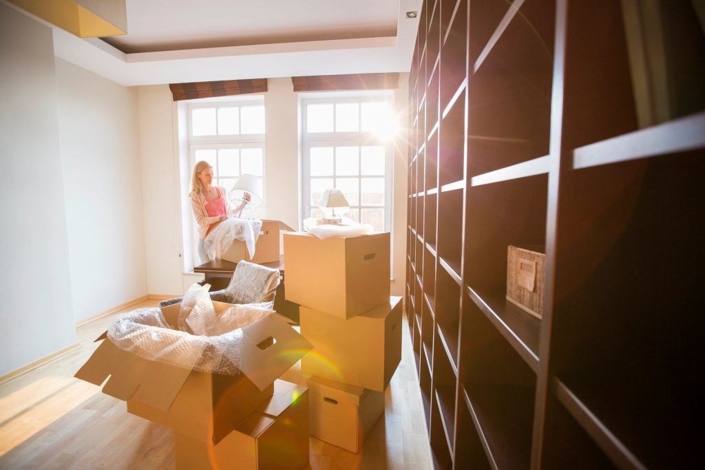 A blonde lady unpacking boxes in a den of a newly moved-into house