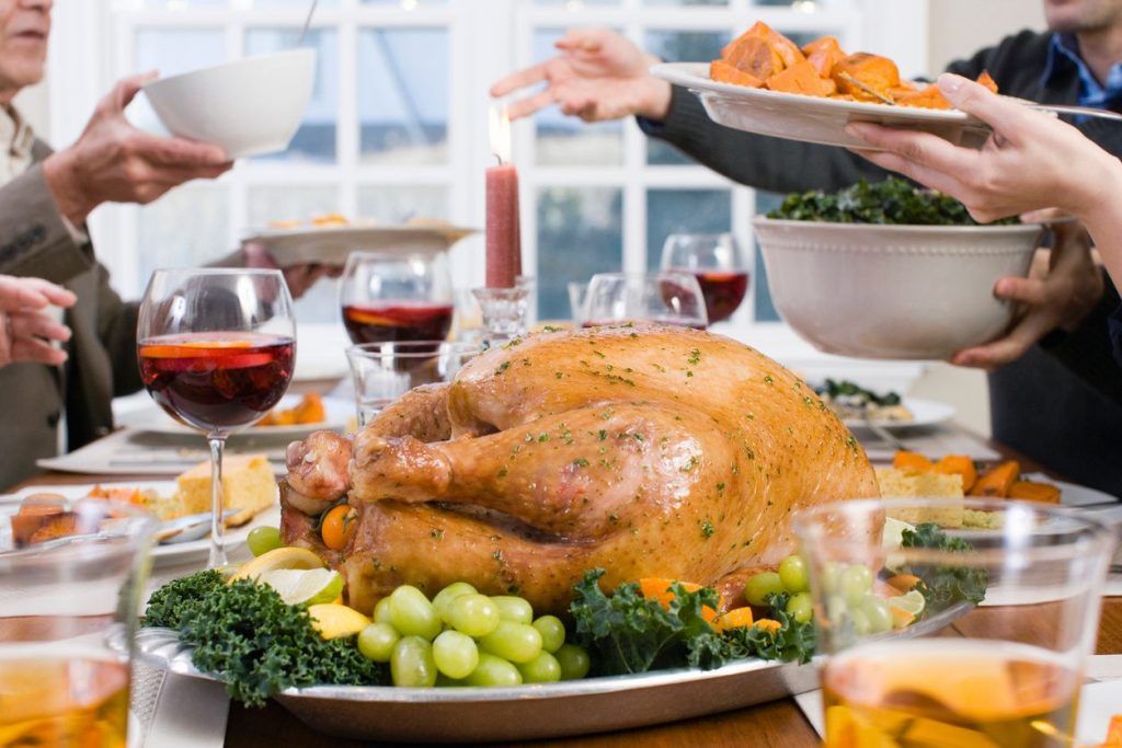 A family passing side dishes over the table during a Thanksgiving dinner