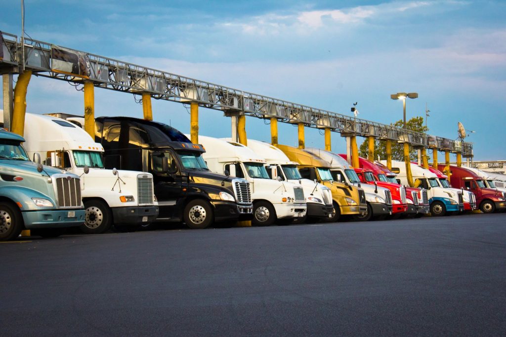 A fleet of commercial semi trucks in a line on a partly cloudy day