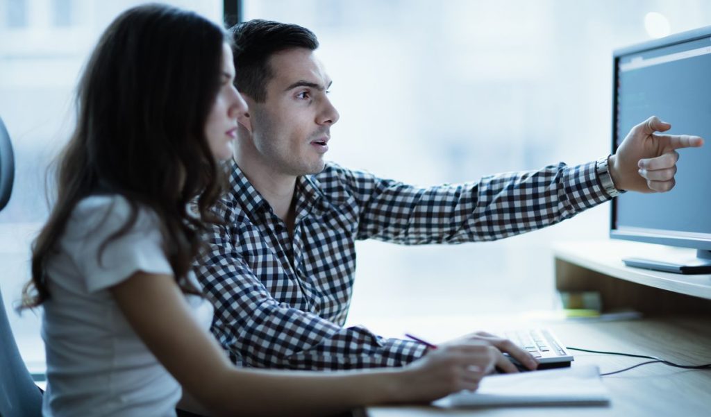 A man and woman collaborating in front of a computer