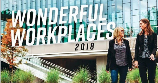 Two women outside of an office building with a glass facade and a Wonderful Workplaces 2018 logo