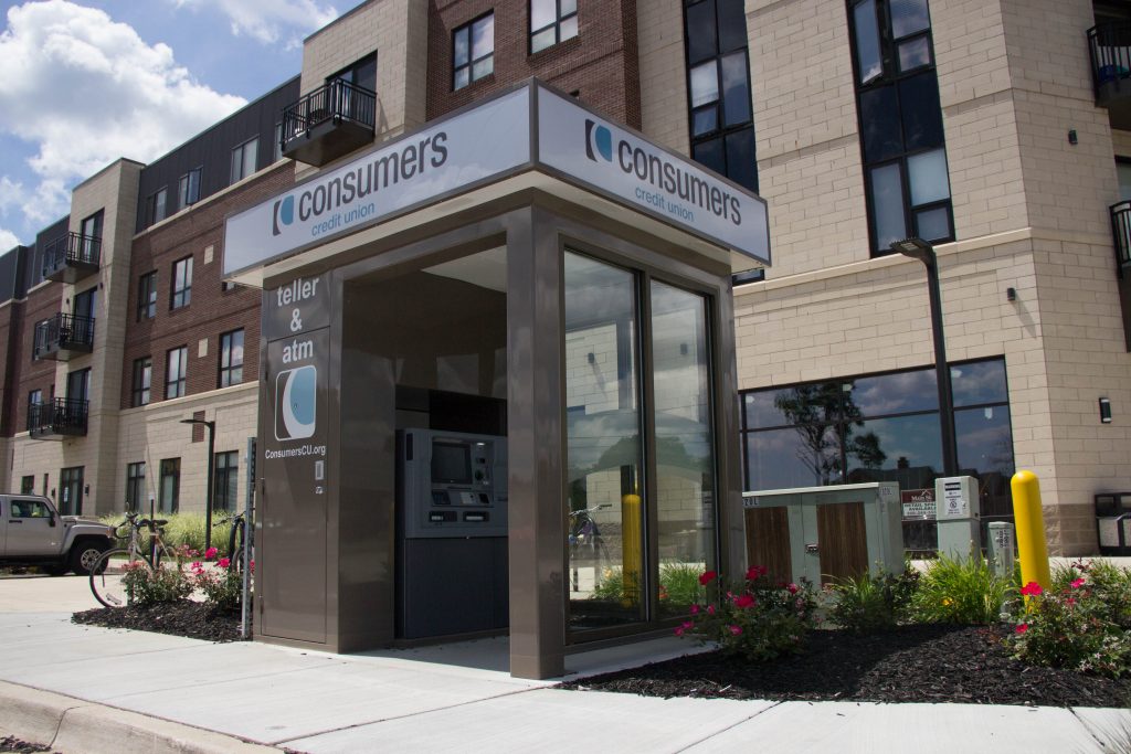 A remote kiosk for Consumers Credit Union Teller & ATM with an apartment building in the background