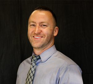 A man wearing a plaid tie smiling for a professional photo