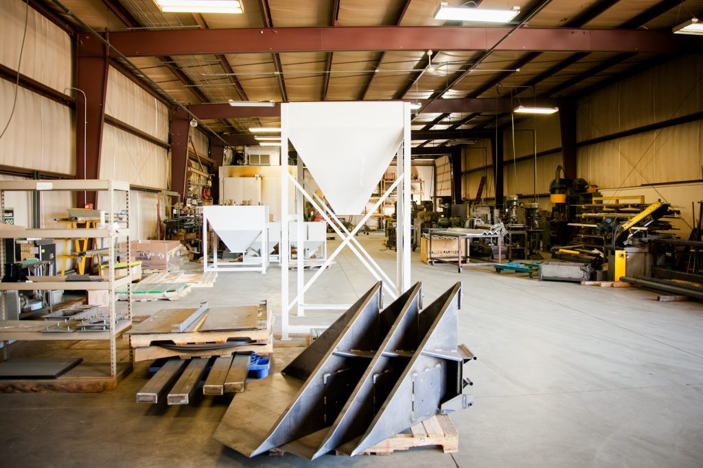 A warehouse outfitted with cantilever shelving with steel stacked on it and other structures fabricated in the workshop