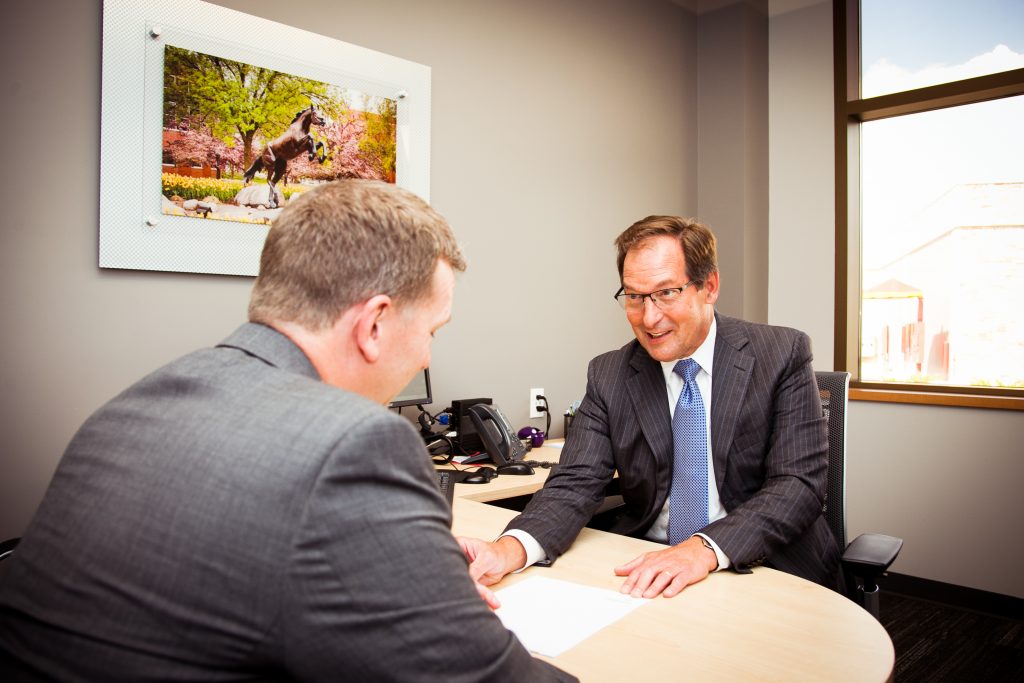 Two men in an office discussing paperwork over a desk