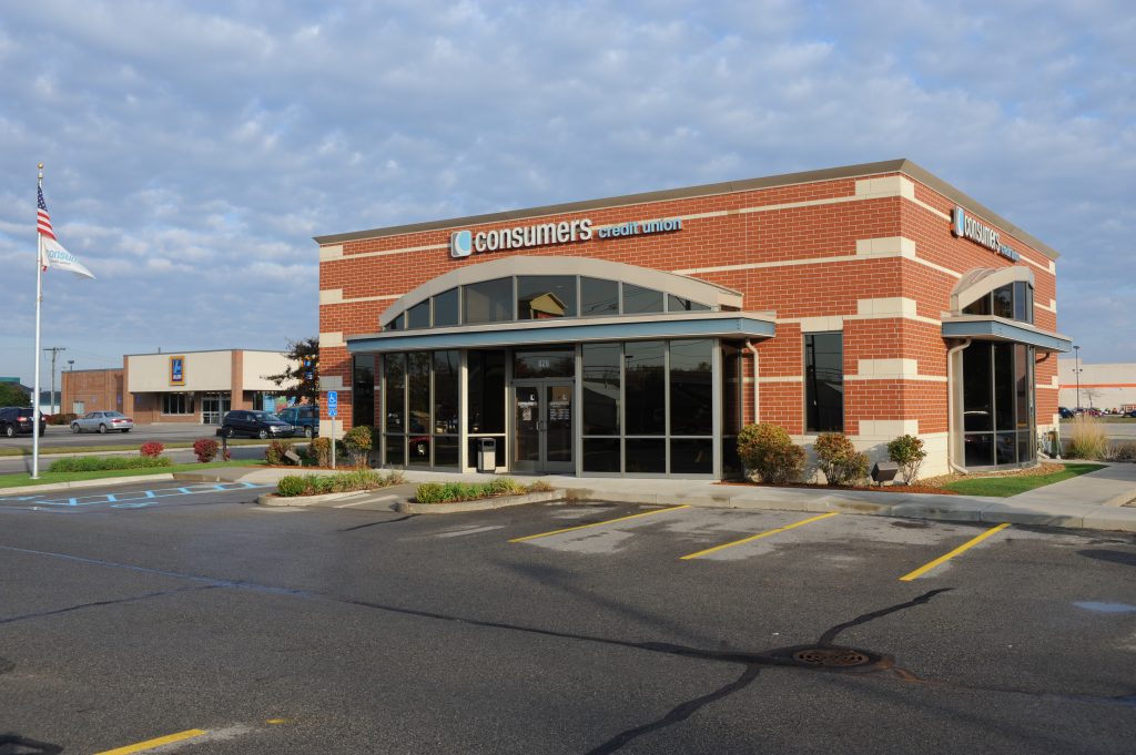 A Consumers Credit Union location with a flagpole to the left and a parking lot in the foreground