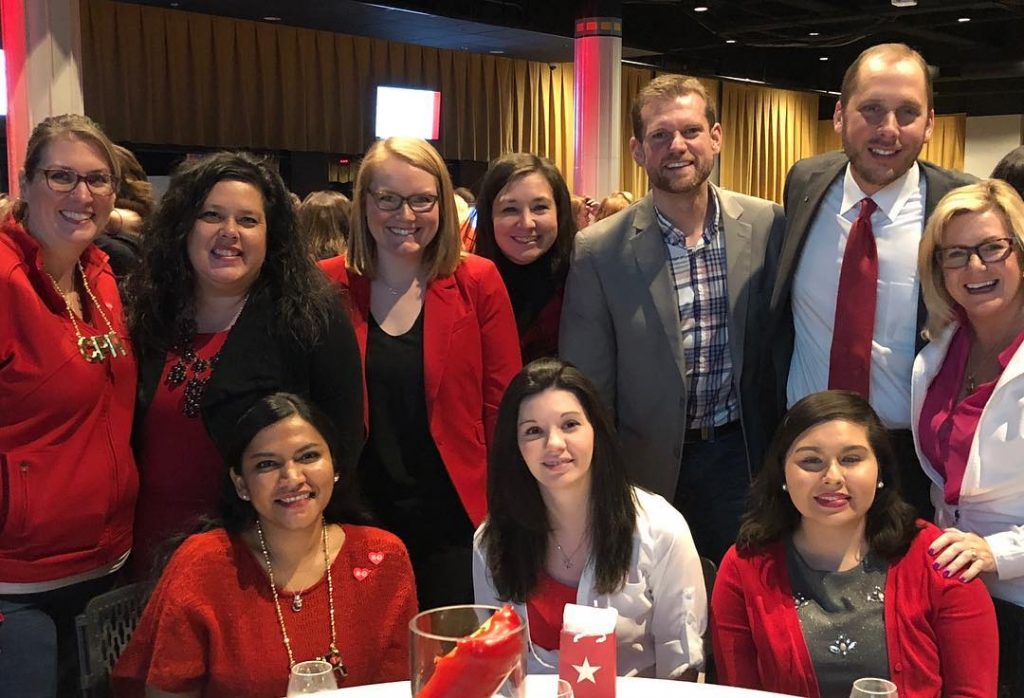 Women and men posing at a large gathering wearing red