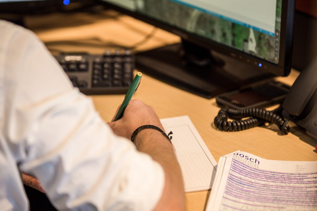 An over-the-shoulder view of a man writing at his desk