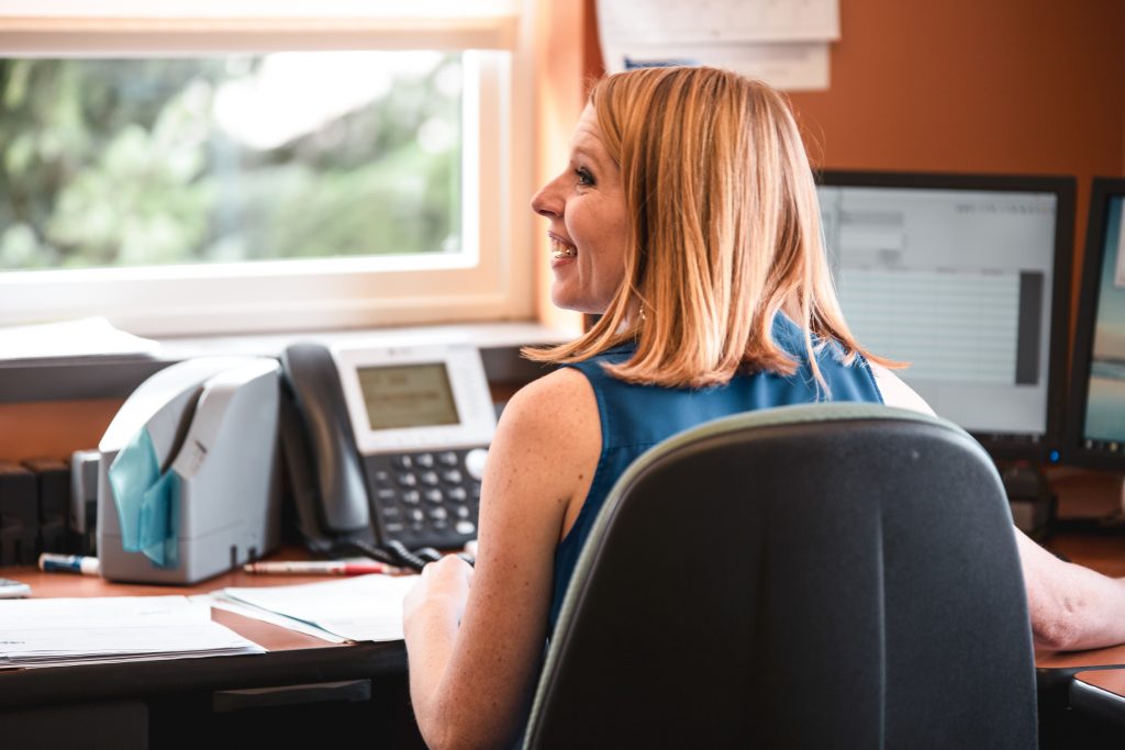 A woman at her desk looking to the left smiling