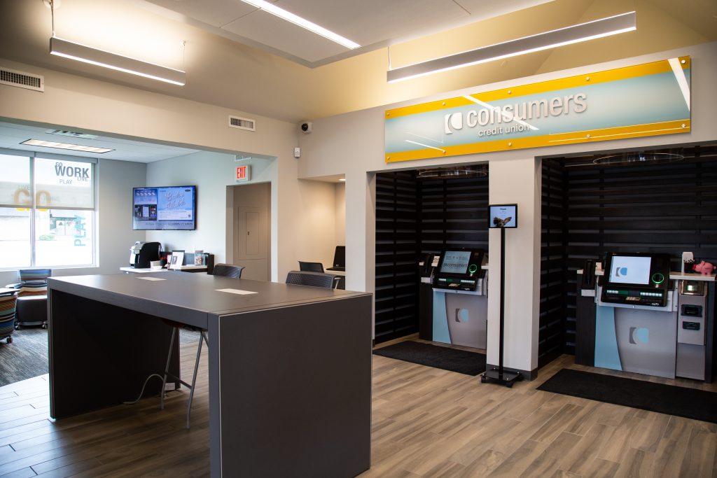 A Consumers Credit Union office with with two personal ATM kiosks and a standing height table in the middle of the room