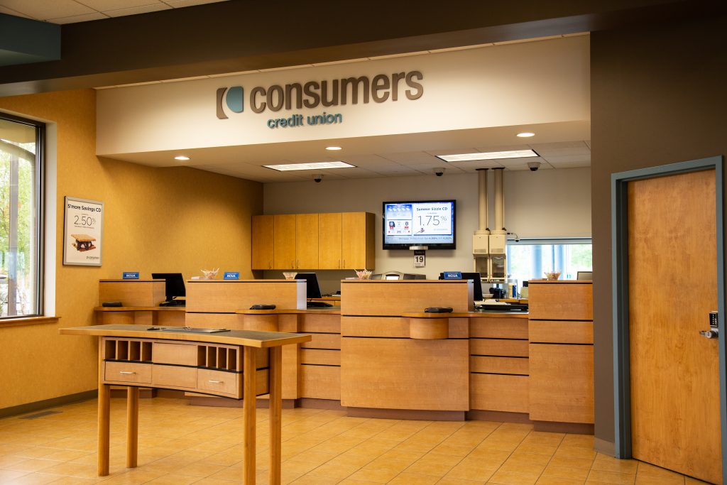 A Consumers Credit Union office front desk with three bank teller windows and a curved bank slip kiosk