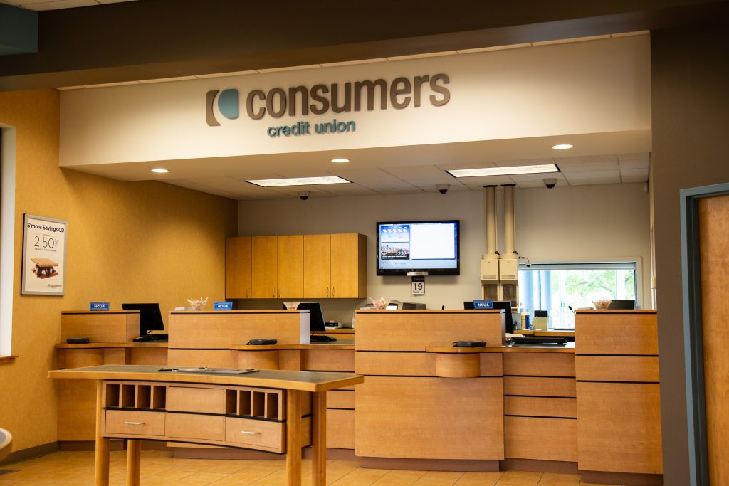 A Consumers Credit Union office front desk with three bank teller windows and a curved bank slip kiosk