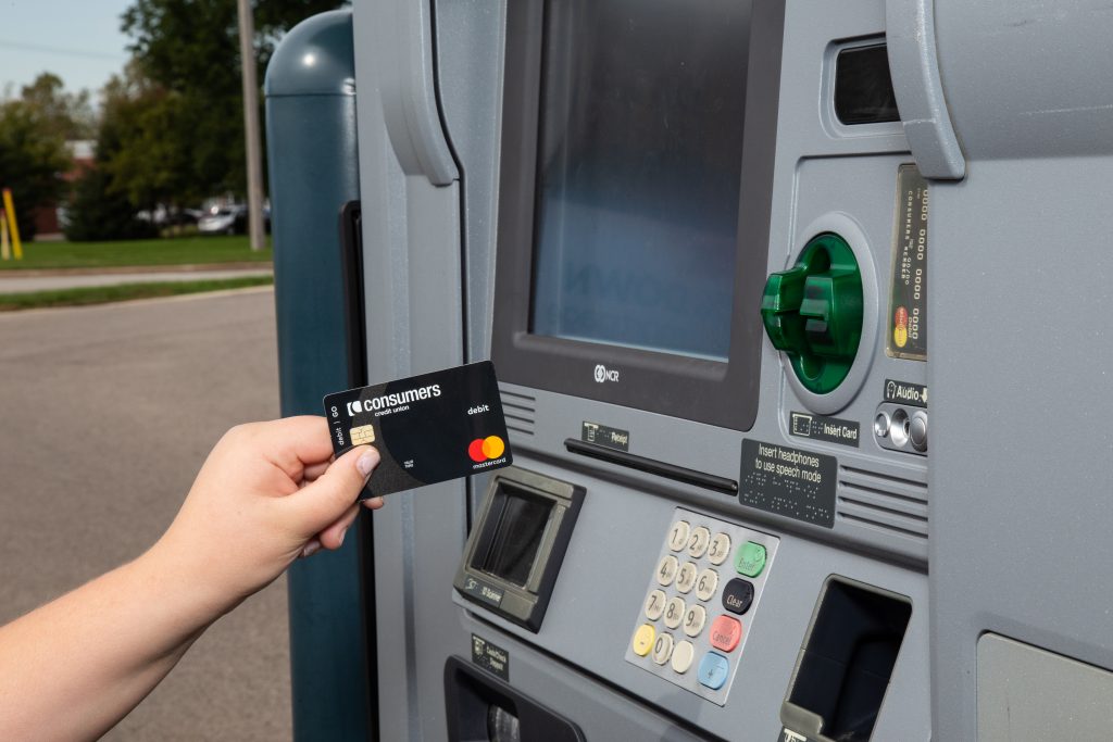 A black Mastercard debit card from Consumers Credit Union being inserted into an ATM