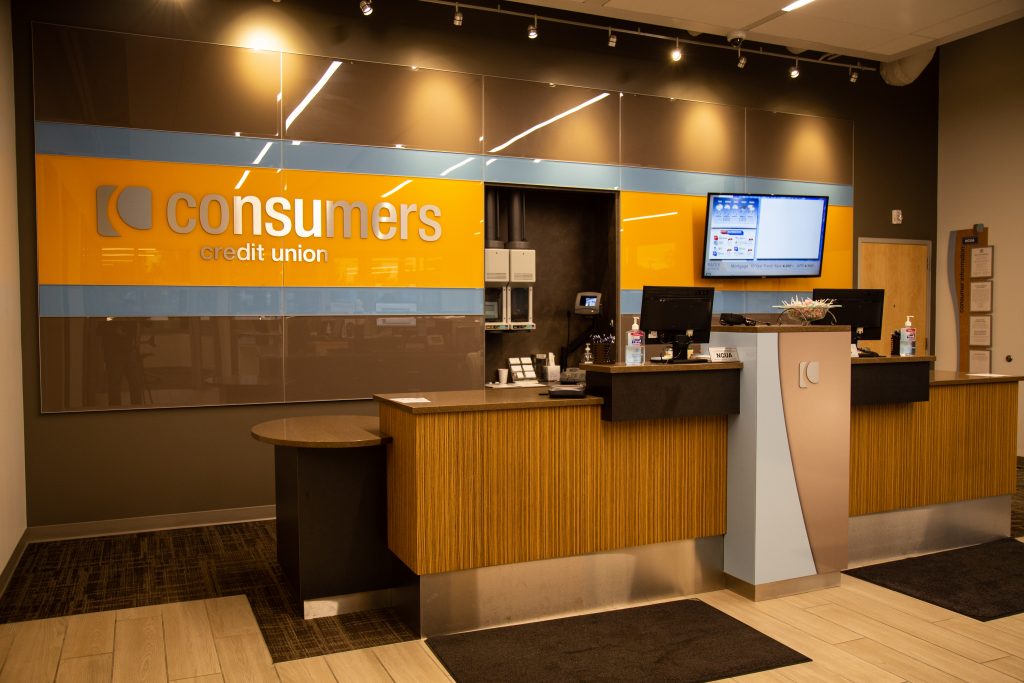 A Consumers Credit Union office with dark wood finish and an orange Consumers sign on a brown wall