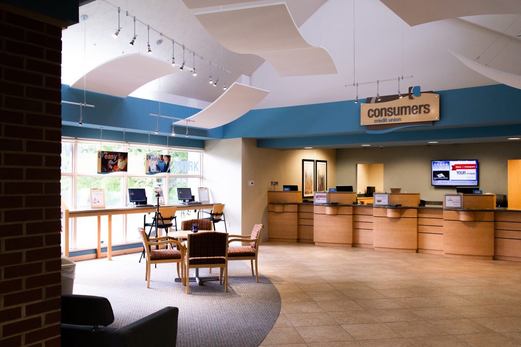 A Consumers Credit Union office with a table and four chairs in front of four teller windows