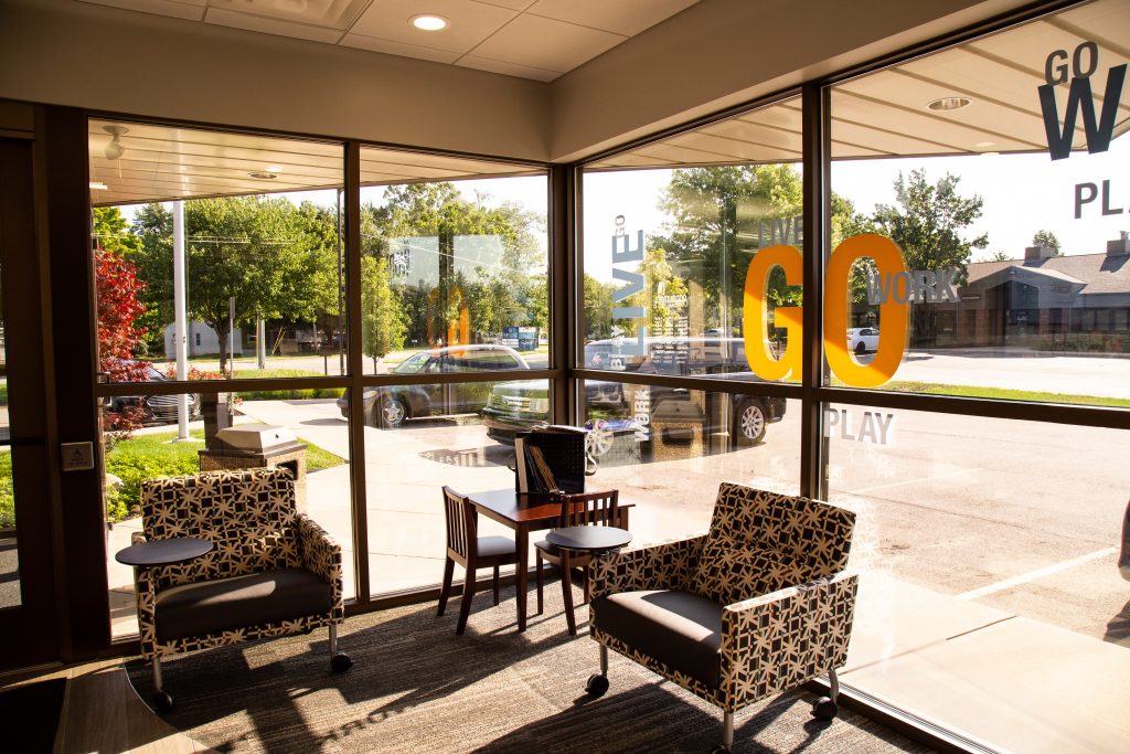 Two armchairs with writing surfaces in front of two large windows in a waiting area of a Consumers Credit Union office