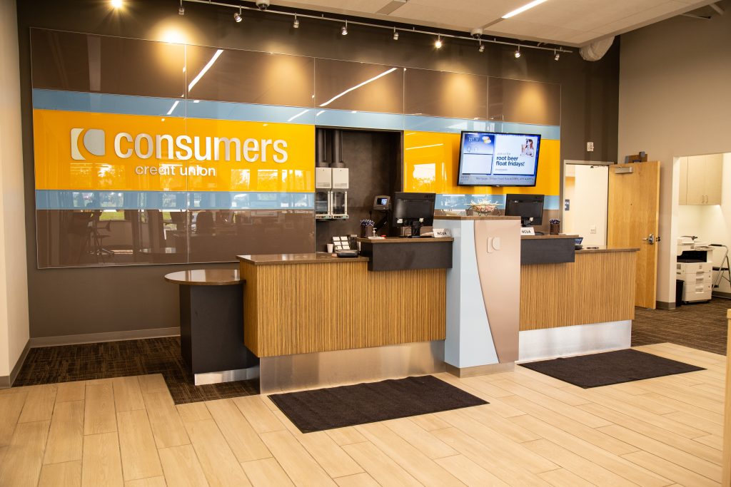 A Consumers Credit Union office with an orange Consumers sign behind the teller counter