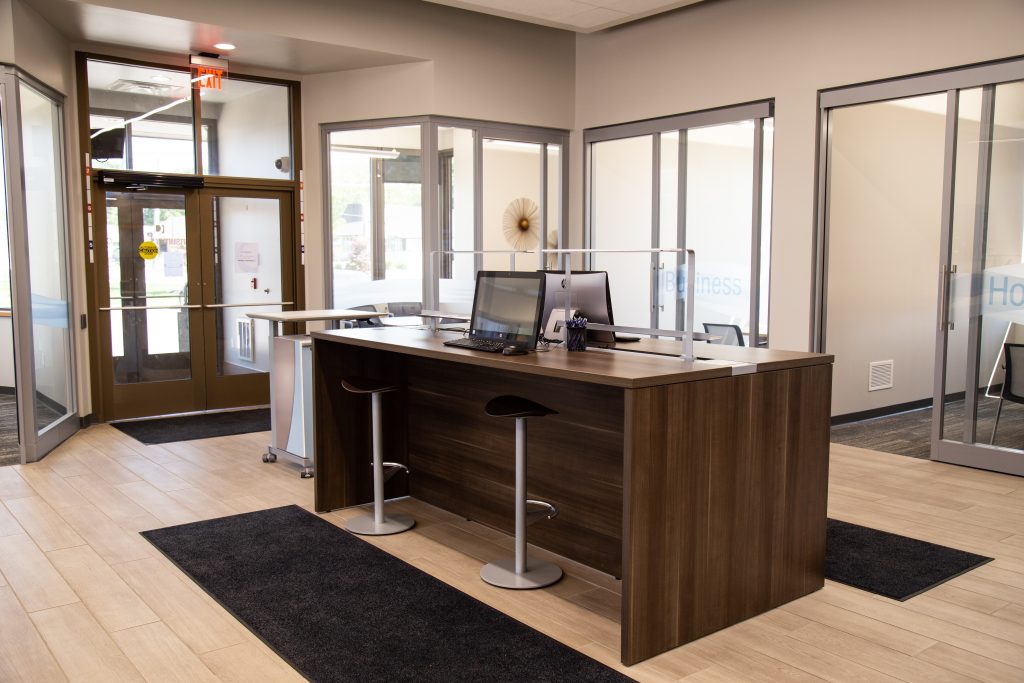 A standing height table with a glass divider between two computers in a Consumers Credit Union office