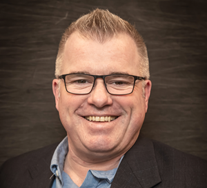 Man with glasses smiling for a headshot