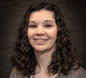 A woman with dark curly hair smiling for a photo