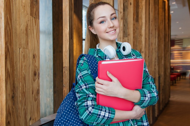 girl with headphones and a binder in hands