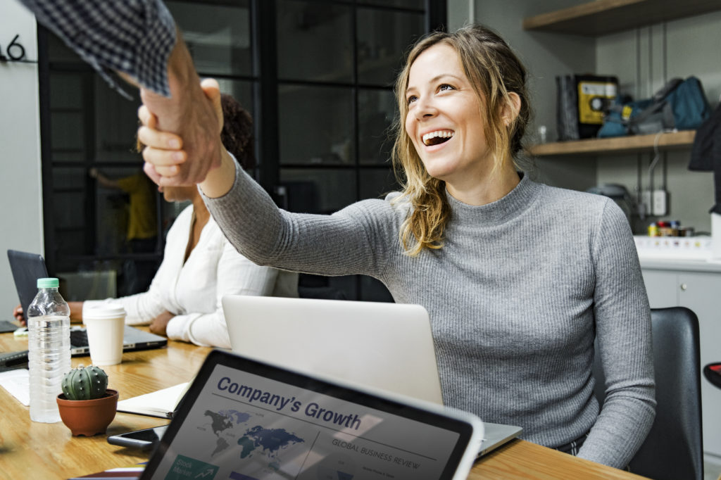 Woman wearing gray sweater shaking someone's hand