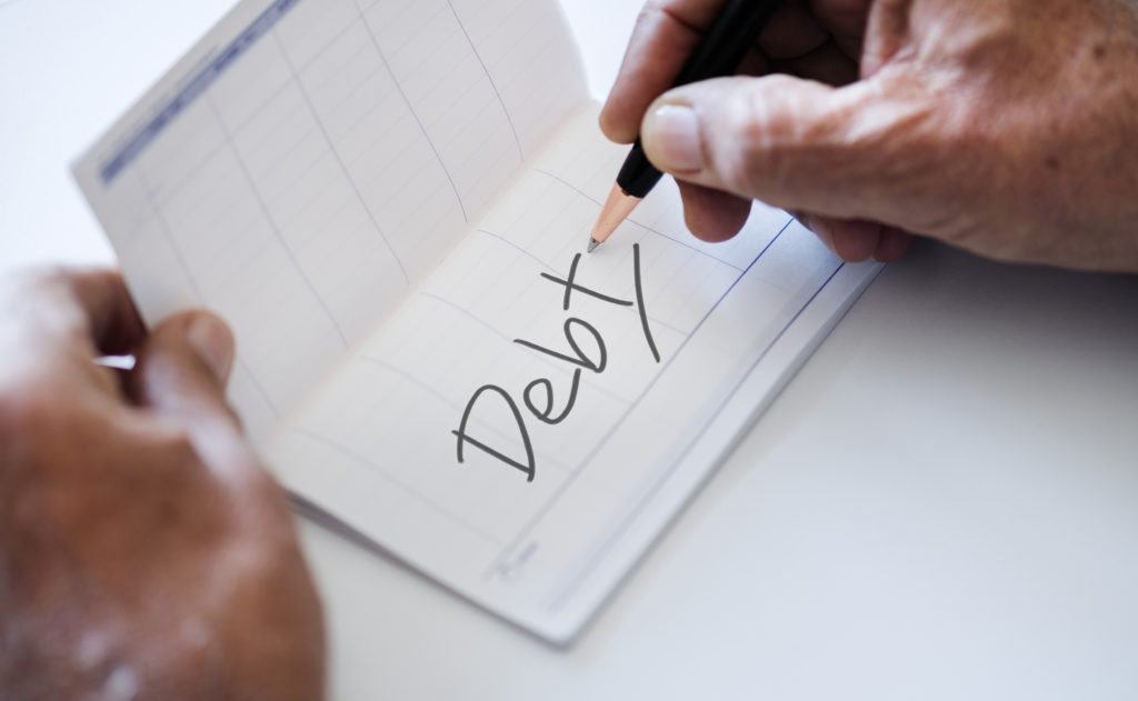 Person writing debt on a piece of paper