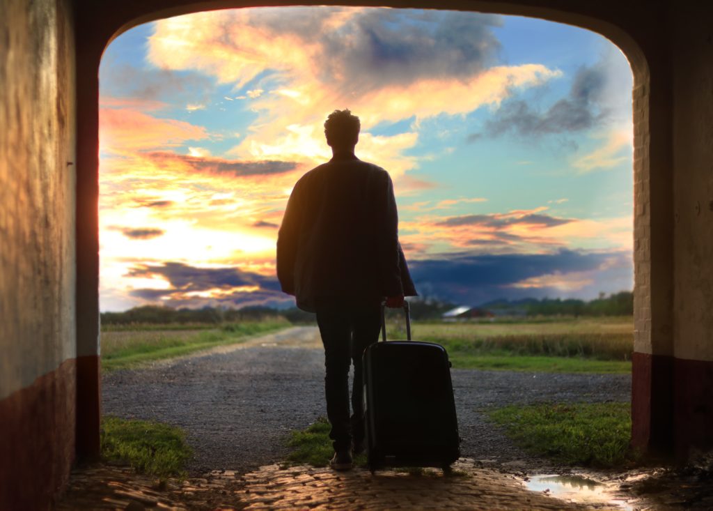 a man stand with a suitcase and is ready to see the world