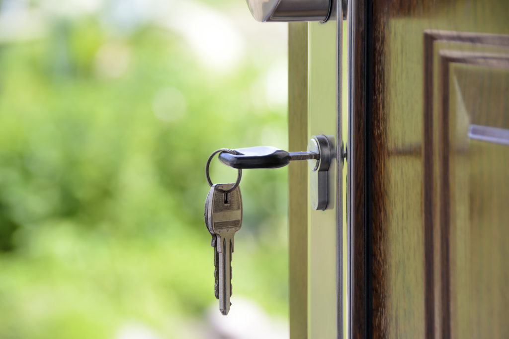 House keys dangling from a lock on the front door of a house