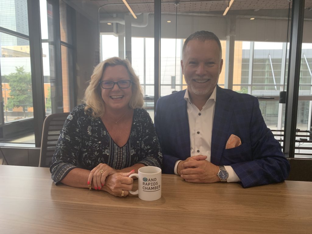 a woman and man sit side by side smiling at a camera