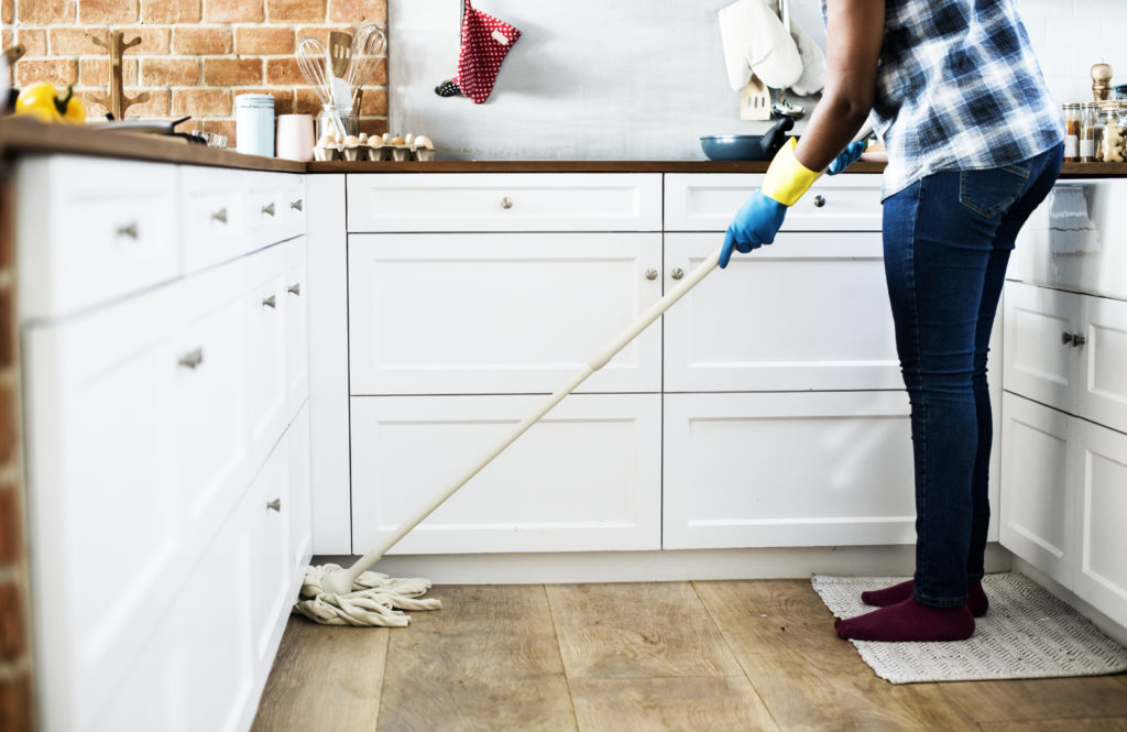 Person wearing gloves mopping a kitchen floor