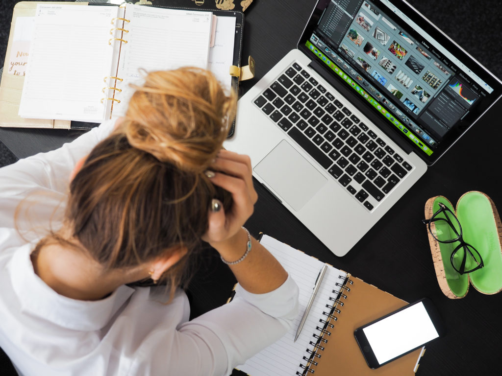 Stressed person with hands on her head working on laptop